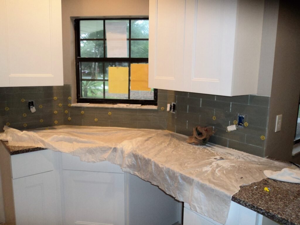 Glass tile backsplash just installed, with the counters still covered