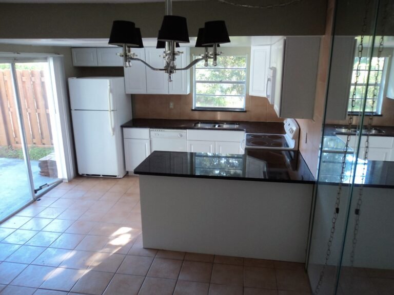 Updated kitchen with white cabinets, dark granite counters and an island