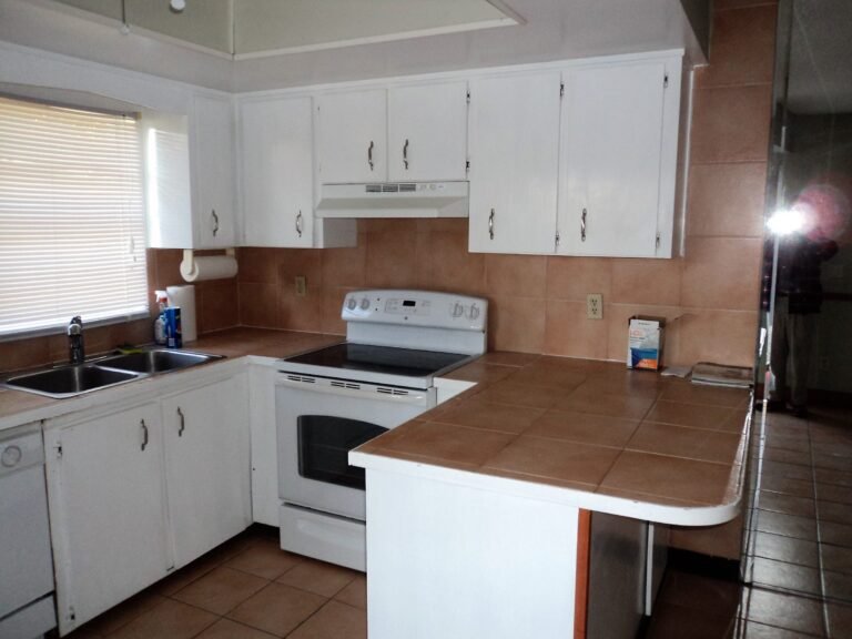 Kitchen before the update, with dated tile countertops and old cabinets