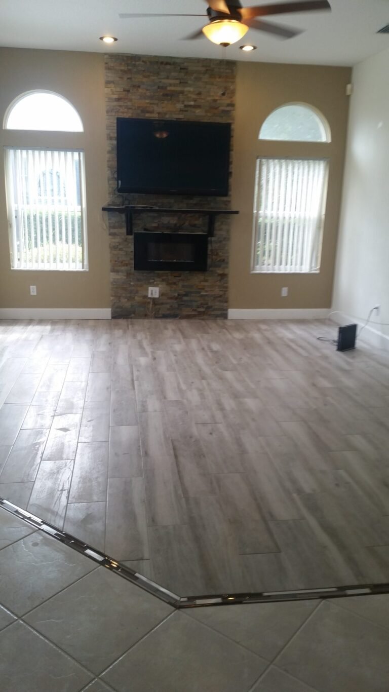 Living room with new wood-look tile flooring and a stone fireplace wall