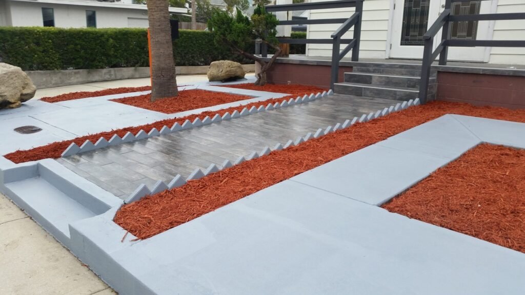 Refinished concrete walkway with edged red mulch beds